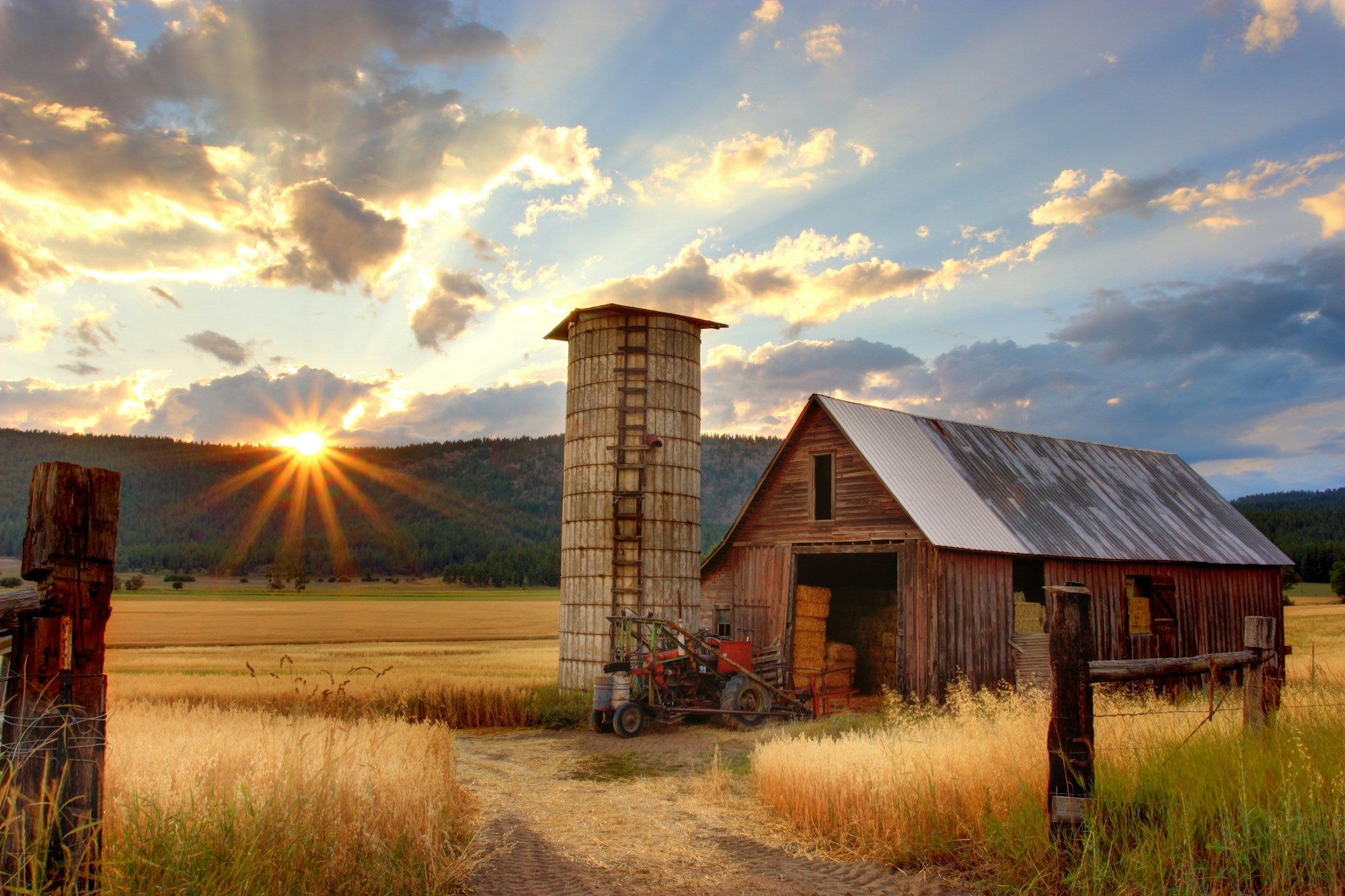 A barn and silo on a family farm at sunset